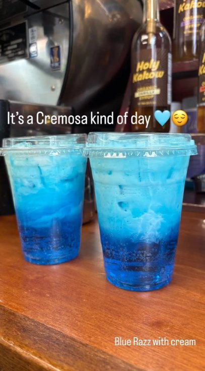 Two bright blue Blue Razz Cremosa drinks with cream on the counter at Riverwoods Coffee